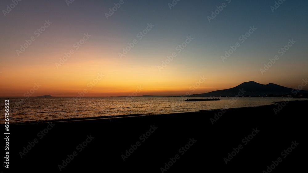 Beautiful scene of dark orange sunset sky and silhouette Mount Vesuvius on the horizon in Italy