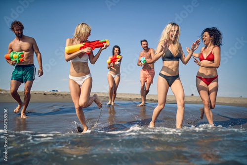 Crazy vacation with happy friends and fun with water gun at beach.