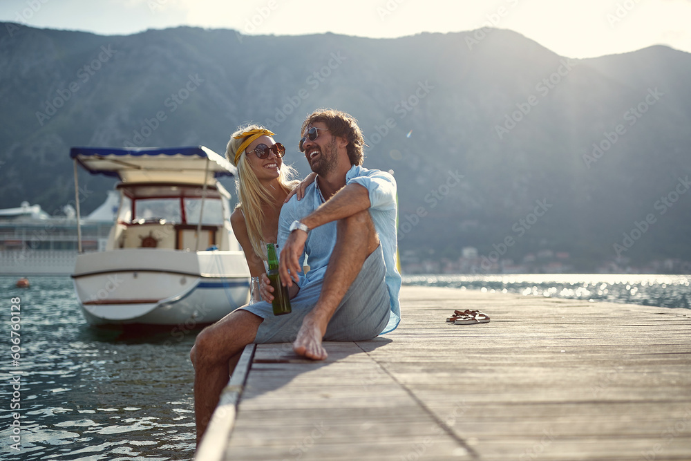 Φωτογραφία A young couple is having a good time while sitting at the dock on the seaside