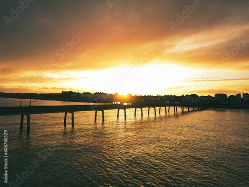 a sunset is reflected by the water  overcast skies