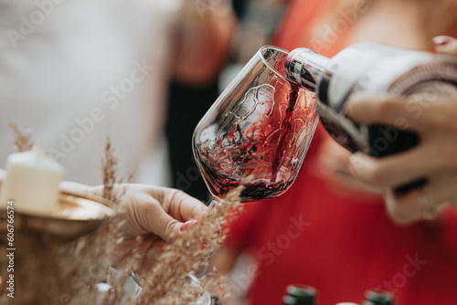 Red wine poured into a glass by a waiter at a tasting in a restaurant.