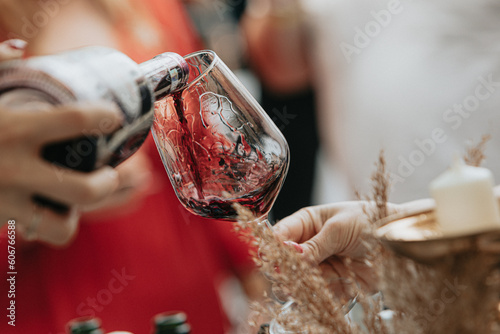 Red wine poured into a glass by a waiter at a tasting in a restaurant.