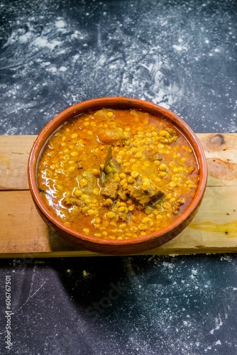 High-angle shot of a lentil soup in a bowl on the wooden board put on the kitchen table