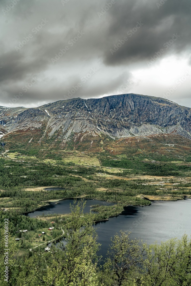 Fototapeta premium Green landscape with lakes and high mountains on the horizon during overcast weather in Norway