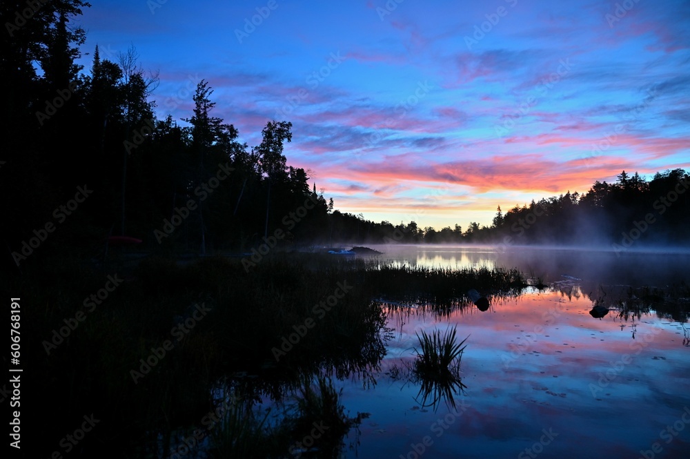 Beautiful shot of a sunset with a cloudy sky over a calm lake and trees