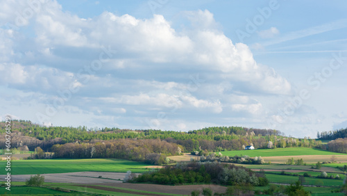 pola i lasy na pagórkowatym terenie, białe obłoki chmury na błękitnym niebie © Andrzej Michaluk