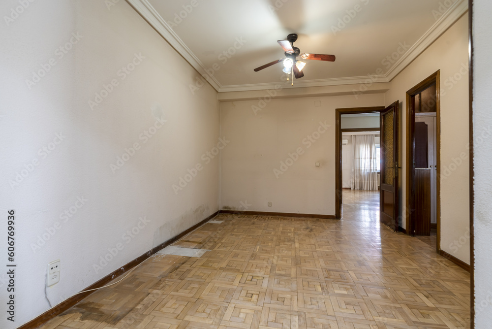 An empty room with a damaged oak parquet floor