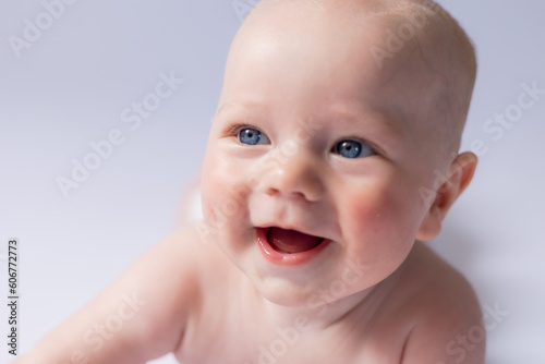 portrait of a cute baby 5 months old on a white background in the studio  smiling looking into the frame. Baby s health  newborn baby  space for text