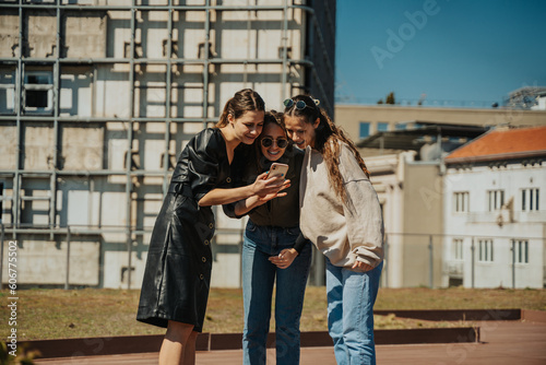 Three lovely girls looking at the phone. Brunette girl  left  showing the pictures to her friends that she took of them