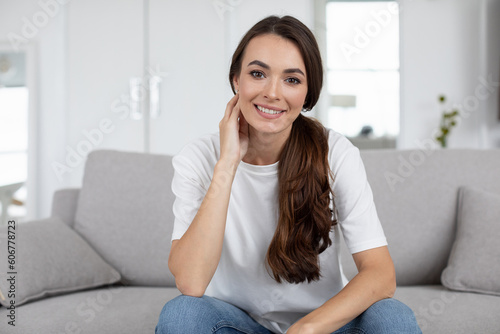 Portrait of a beautiful woman sitting on the sofa looking at the camera, online