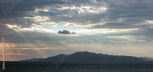 Sunbeam through overcast during sunset over Cyclades island Greece. Dark blue wavy Aegean sea. © Rawf8