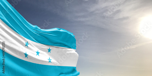 Honduras national flag cloth fabric waving on beautiful grey sky Background.