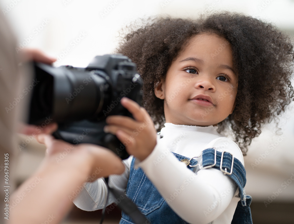 Cute kid playing digital camera learn to take picture. Afro hair multiracial girl interested in camera and lens to be adorable photographer. Cheerful little child holding equipment with fun, portrait. Cute kid playing digital camera learn to take picture. Afro hair multiracial girl interested in camera and lens to be adorable photographer. Cheerful little child holding equipment with fun, portrait.