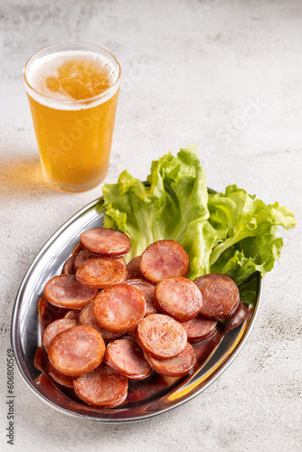 Sliced       fried pepperoni sausage with glass of beer on the table.
