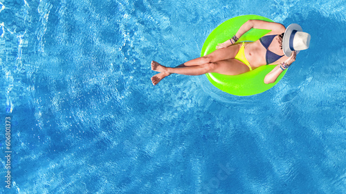 Beautiful woman in hat in swimming pool aerial drone view from above  young girl in bikini relaxes and swims on inflatable ring donut and has fun in water on tropical vacation on holiday resort 