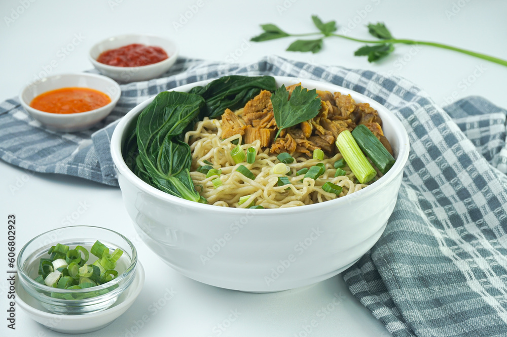 Noodles with Chicken, in Indonesia it is known as Mie Ayam. Served with green vegetable chili sauce in a bowl on white background