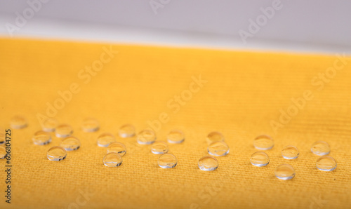 water repellent fabric, yellow fabric does not absorb water drops. Laboratory water repellent test. Selective focus.
