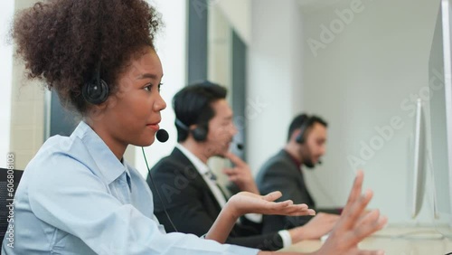 African America call center wearing headphone looking at computer and talk with customer via phone. Helping customer and introduce the new product with good service mind in the office.