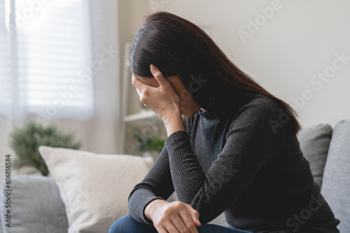 Unhappy anxiety young Asian woman covering her face with pillow on the cough in the living room at home Fototapet