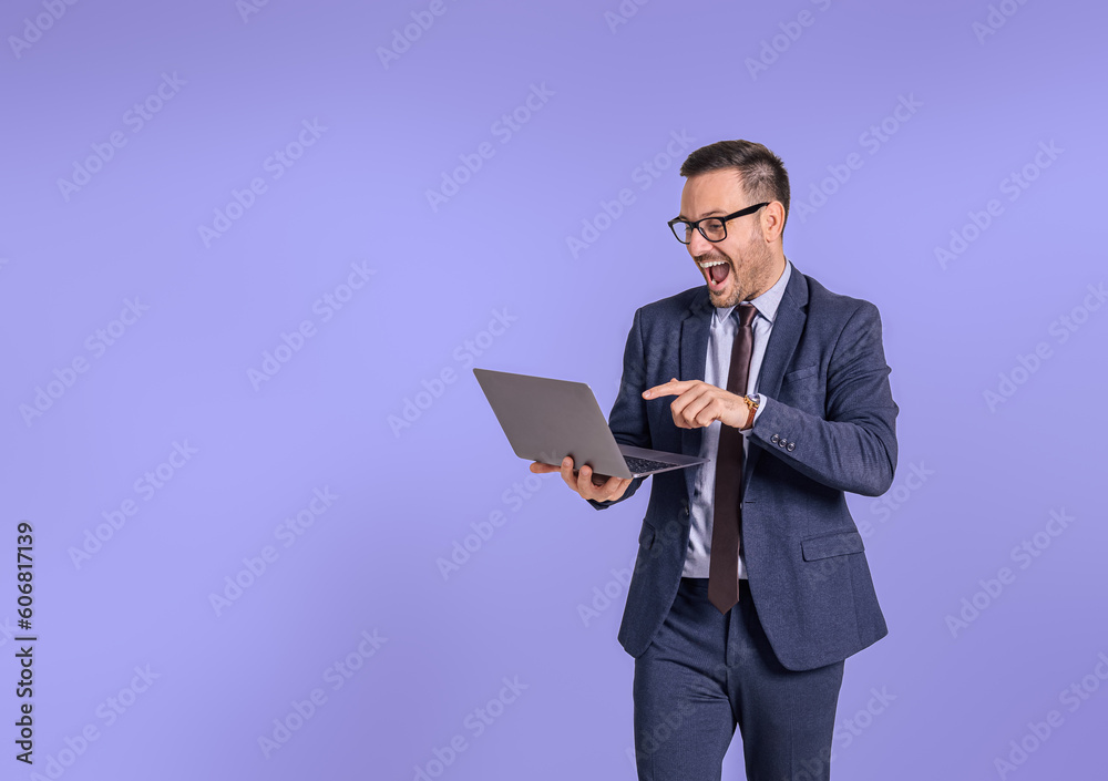Male entrepreneur screaming cheerfully while attending online meeting isolated on blue background.Young businessman shouting ecstatically and celebrating project success while using wireless computer Male entrepreneur screaming cheerfully while attending online meeting isolated on blue background.Young businessman shouting ecstatically and celebrating project success while using wireless computer