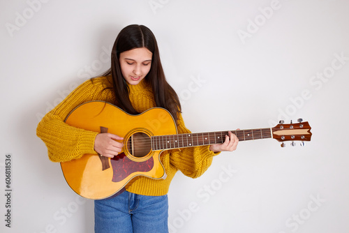 A young girl plays the acoustic guitar. 