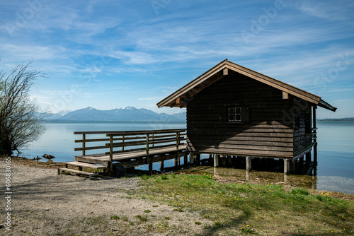 retrieve a wooden cottage in the water with the mountains with snow on the tops in the background © Chris Willemsen 