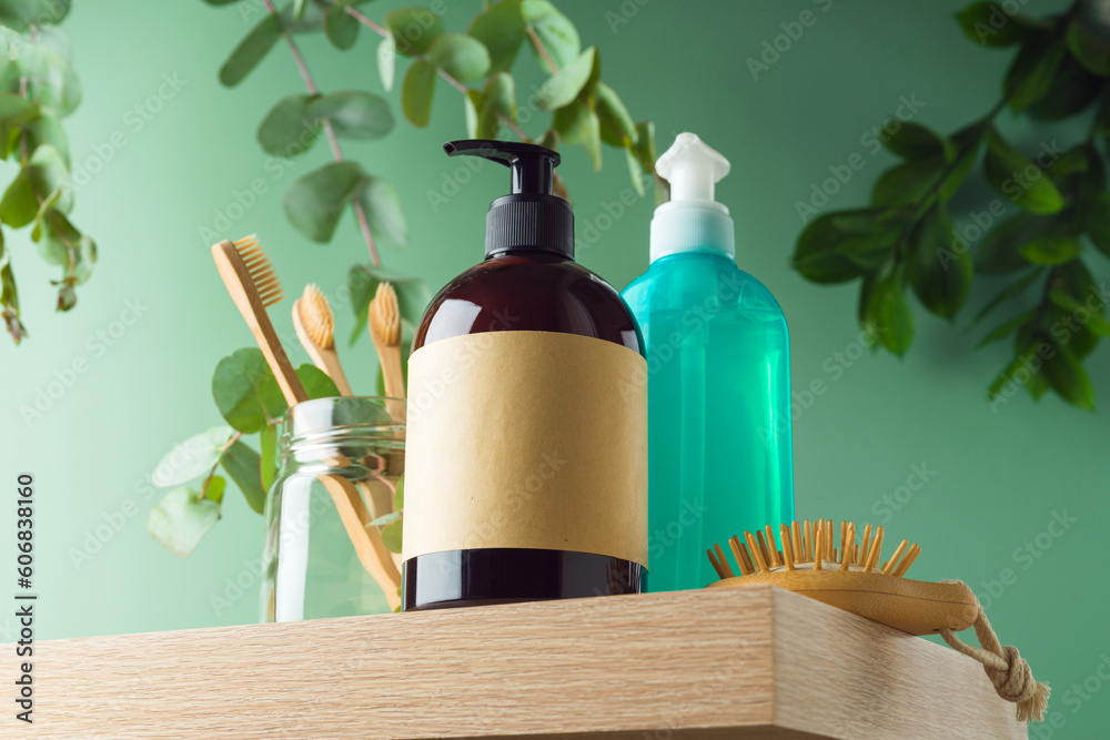 Φωτογραφία Natural cosmetics bottle with labels and bamboo toothbrush  on wooden shelf over green leaves background