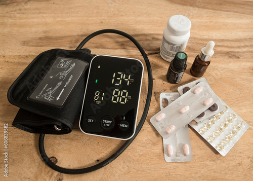 tabletki, ciśnieniomierz, lekarstwa, termometr oraz woda na blacie stołu