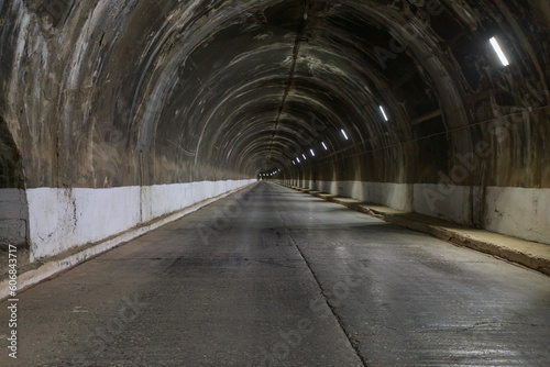 Tunnel with road inside mountain with arch dam.