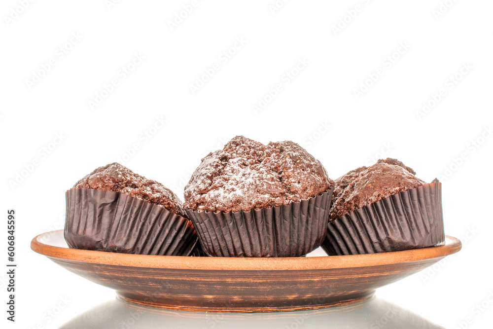 Four homemade chocolate muffins on a clay plate, macro, isolated on white background. Four homemade chocolate muffins on a clay plate, macro, isolated on white background.