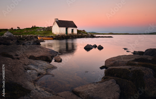 Breathtaking lakeside sunrise scenery of fisherman's hut and wooden boat reflected in lake at Screebe in Connemara National park ,county Galway ,Ireland  photo