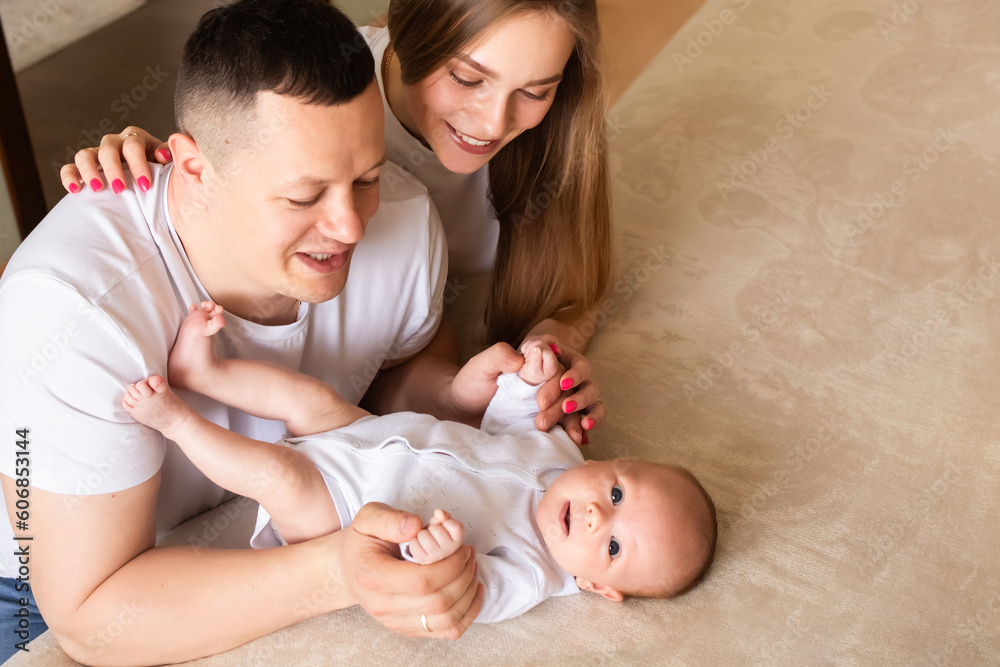 parents play with a baby at home on a bed covered with a linen bedspread. family concept. happy parenthood concept. parents play with a baby at home on a bed covered with a linen bedspread. family concept. happy parenthood concept.
