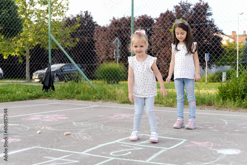 Two little girls playing hopscotch ,We love to play together