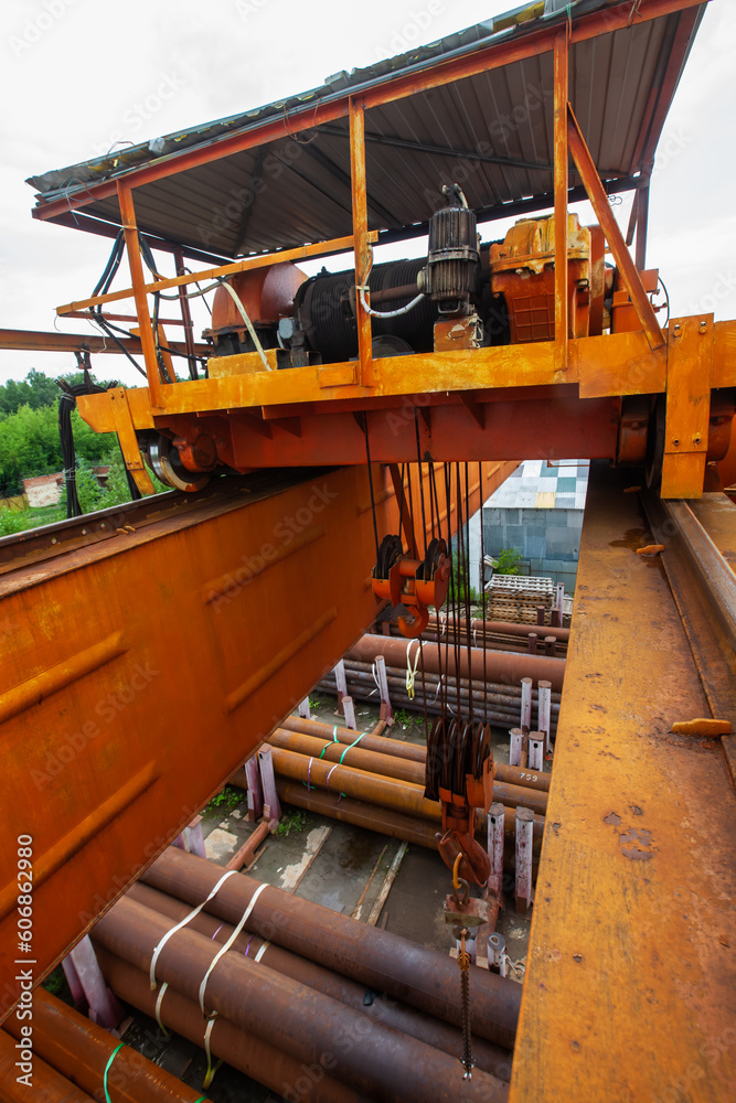 Overhead crane boom and hook from top to bottom closeup. Rusted pipes down Overhead crane boom and hook from top to bottom closeup. Rusted pipes down