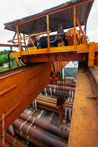 Overhead crane boom and hook from top to bottom closeup. Rusted pipes down