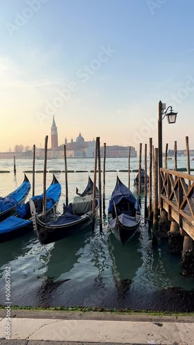 Vertical video of a beautiful sunrise in Venice, Italy where you can see the sea, the gondolas and old buildings.