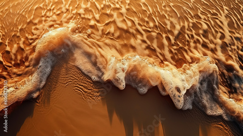 Photo of small wave breaking on sandy beach - sunset, warm lighting - background texture
