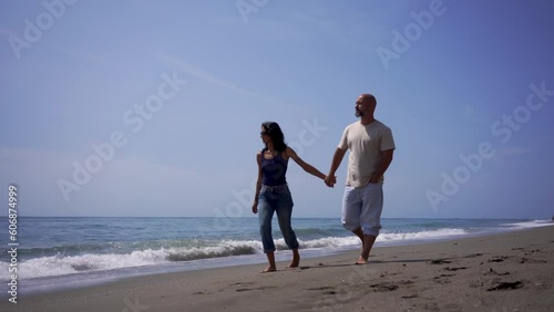 a guy with a girl a couple in love walks on the beach barefoot on the sand