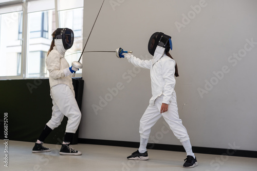 Two girl fencing athletes fight on professional sports arena 