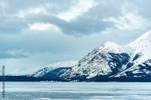 Incredible snow capped mountains in the winter time with a frozen lake in foreground. Taken in Atlin, British Columbia near Alaska, Yukon Territory, Canada. 