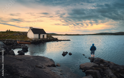Obraz na płótnie Beautiful sunset nature scenery with man on the rock watching sunrise at Fisherman's hut, screebe, connemara national Park in County Galway, Ireland w salonie