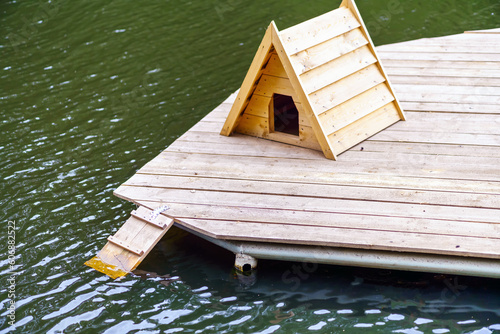 Duck house made of wood on the pond with decking for lifting