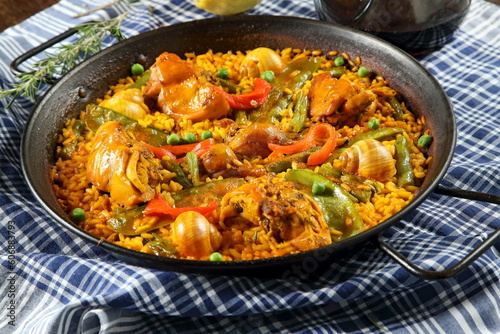 Valencian paella with porrenes of red wine on the wooden table