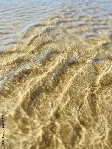 Transparent sea water and sandy bottom, ripples on the sea water, natural sea water background