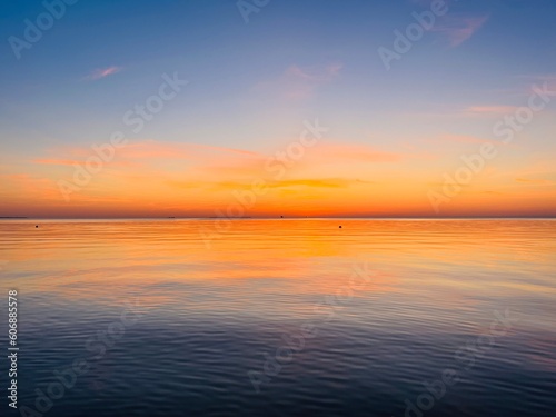 Orange sky after the sunset at the sea, evening sea horizon  © Oksana