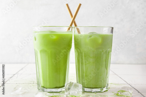 Iced green matcha latte in glasses with a straw on white background. Cold summer drink