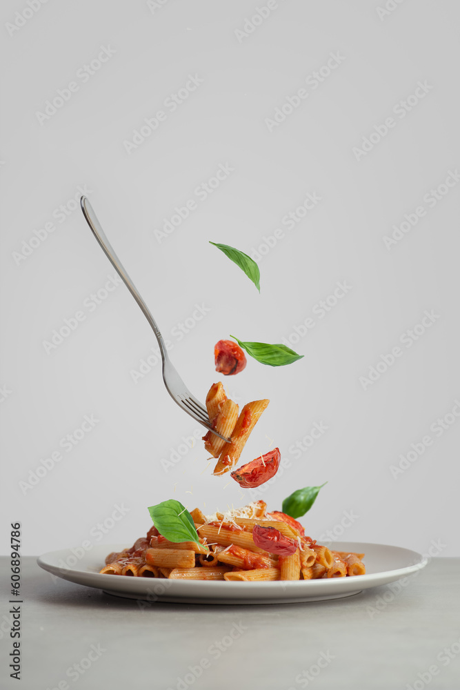 Fotografie Pasta on a fork with tomatoes and basil falling into a plate