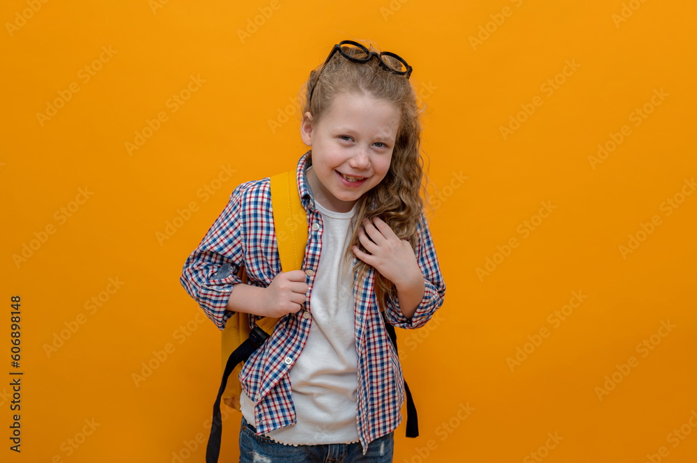 cute joyful girl child 6-7 years old on an isolated yellow background in with a school backpack. High quality photo cute joyful girl child 6-7 years old on an isolated yellow background in with a school backpack. High quality photo