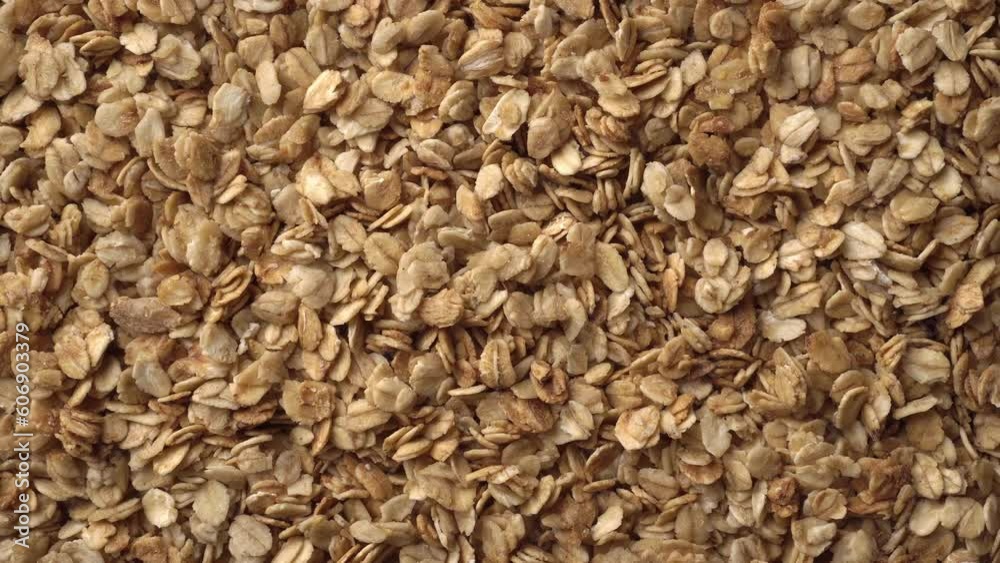Oatmeal or crunchies form a slowly rotating textured background. Concept of healthy food - cereal breakfast. Close up, top view. Copy space for advertising text Oatmeal or crunchies form a slowly rotating textured background. Concept of healthy food - cereal breakfast. Close up, top view. Copy space for advertising text