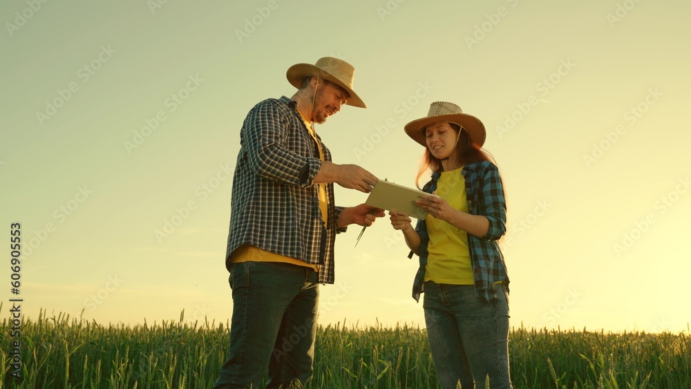 Agricultural business concept. Two business farmers, man and woman, shake hands tightly. Deal. A farmer and a businessman talk in wheat field, make a deal, use a tablet. Growing food. work companions